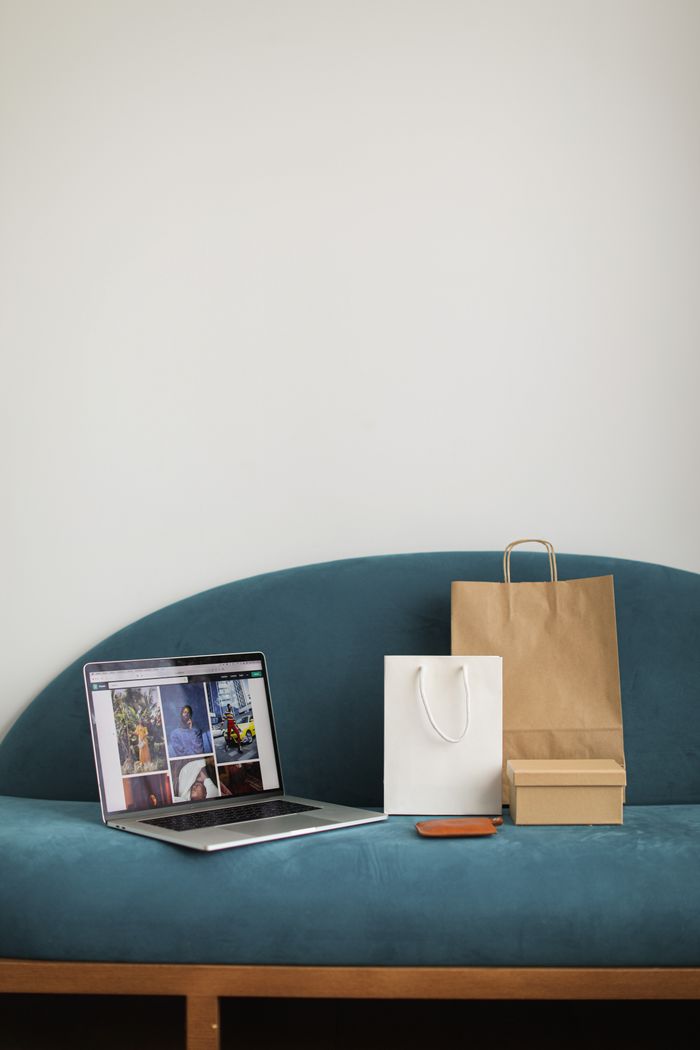 Shopping bags and laptop on sofa, perfect home e-commerce concept for online shopping enthusiasts.
